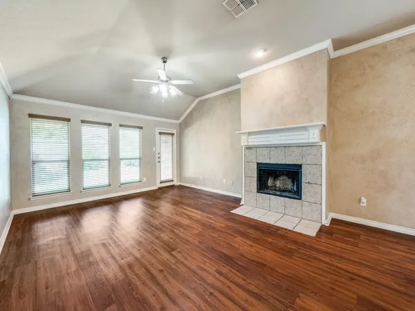 a view of an empty room with wooden floor fireplace and a window