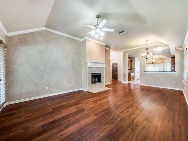 a view of an empty room with wooden floor fireplace and a window
