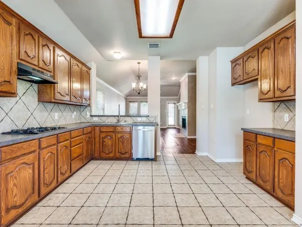 a large kitchen with stainless steel appliances wooden cabinets and a stove top oven