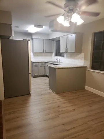 a large kitchen with kitchen island a sink dishwasher a refrigerator and a stove with wooden floor