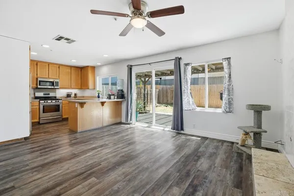 a kitchen with stainless steel appliances granite countertop a refrigerator a stove top oven a sink dishwasher and white cabinets with wooden floor