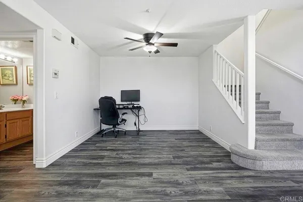 a view of a workspace with wooden floor and a ceiling fan