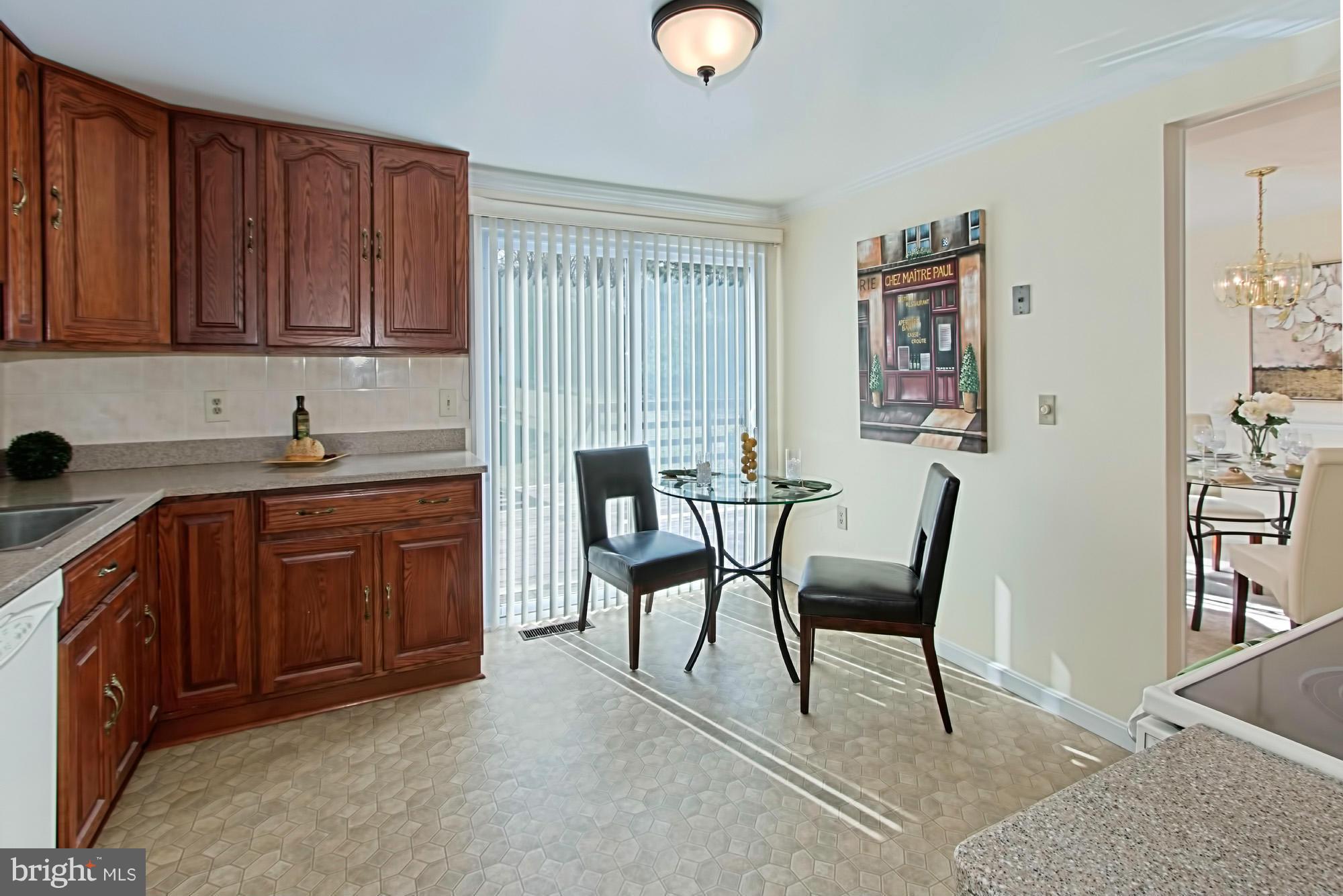 9505 Burning Branch Road Burke, VA 22015 - Photo 14 of 30 a kitchen with a table chairs and wooden cabinets
