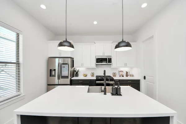 a kitchen with stainless steel appliances kitchen island a table chairs sink and cabinets