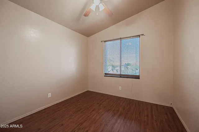 an empty room with a hardwood and ceiling fan