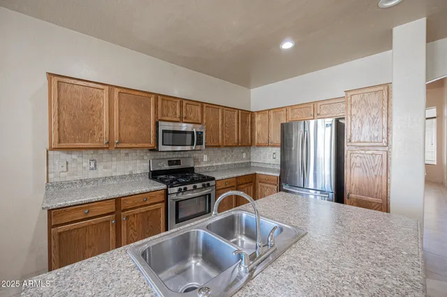 a kitchen with stainless steel appliances granite countertop a sink stove refrigerator and cabinets