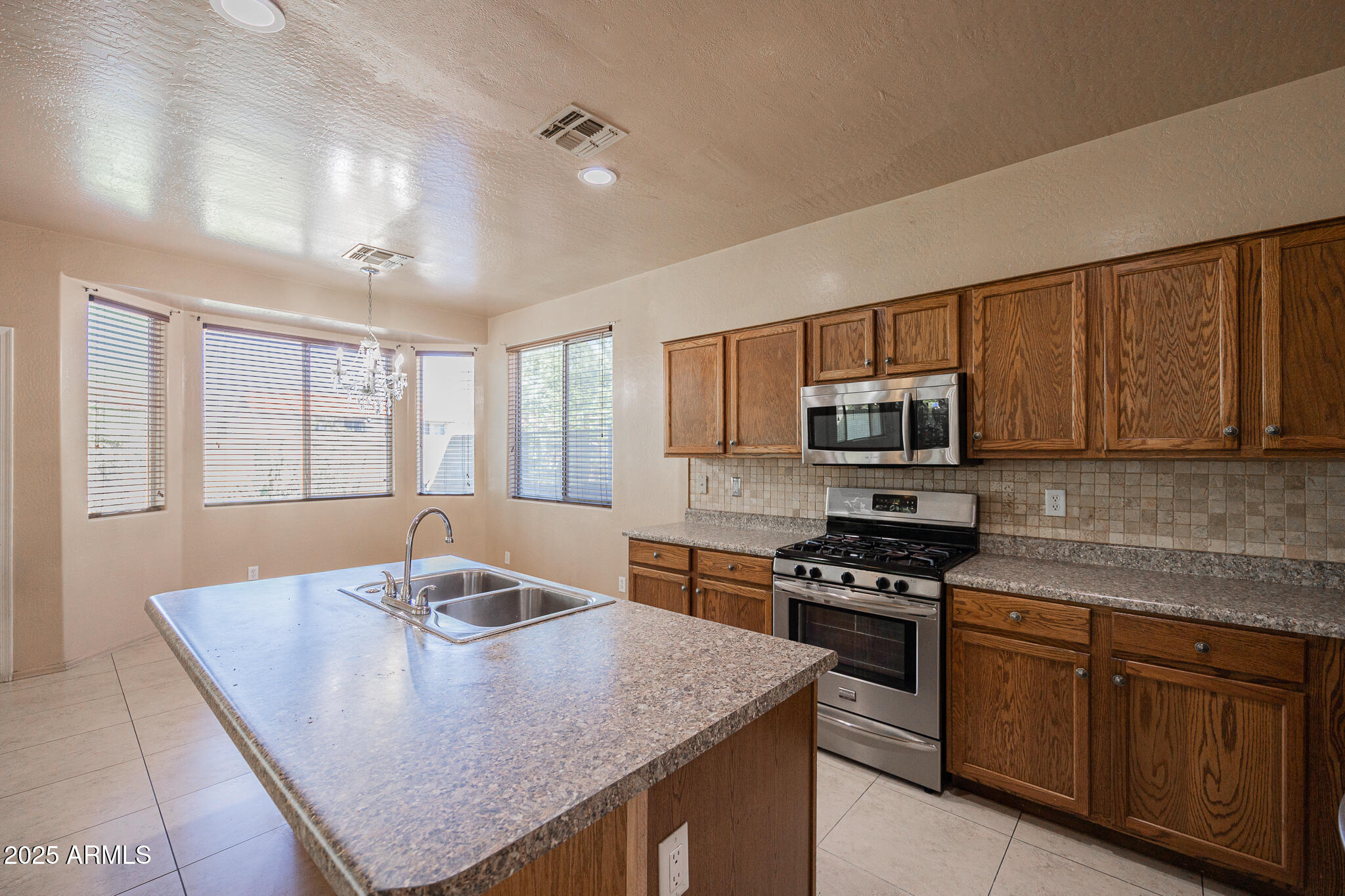 730 West Kent Place Chandler, AZ 85225 - Photo 10 of 29 a kitchen with stainless steel appliances granite countertop a stove a sink dishwasher a microwave oven with a dining table and chairs