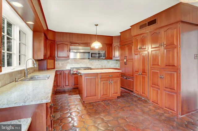 a kitchen with stainless steel appliances granite countertop a sink a stove and a wooden cabinets