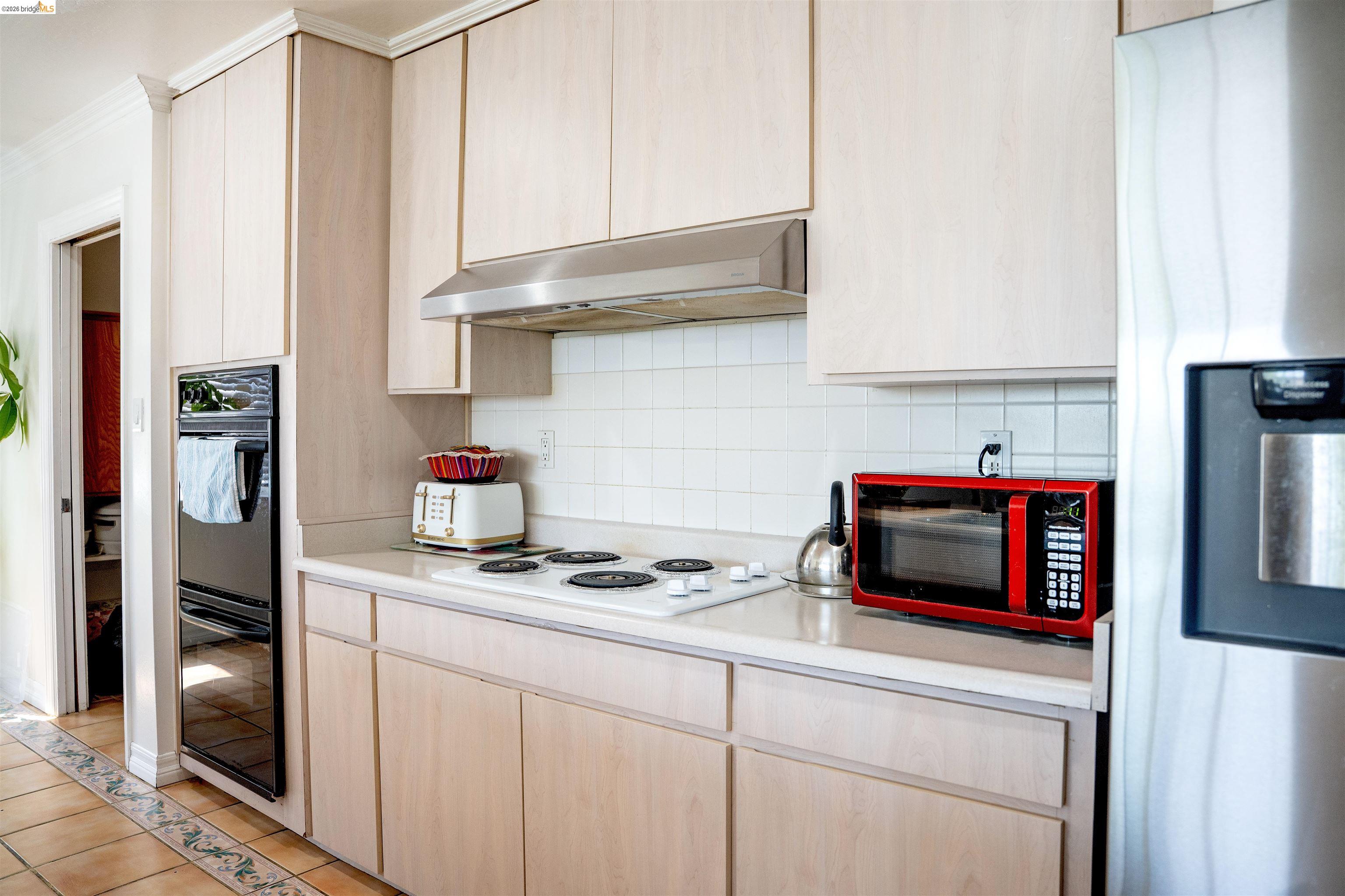64 Washington Street Novato, CA 94947 - Photo 5 of 21 Kitchen featuring light wood-finish cabinetry, a built-in double oven, and a stainless steel refrigerator