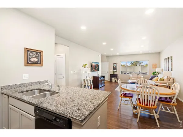 a dining hall with stainless steel appliances granite countertop a dining table and chairs with wooden floor