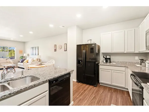 a kitchen with a sink dishwasher a refrigerator a stove and white cabinets with wooden floor