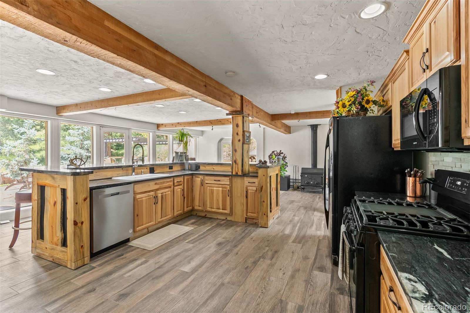 1053 Red Moon Road Evergreen, CO 80439 - Photo 31 of 50 a kitchen with stainless steel appliances granite countertop a stove a sink dishwasher a refrigerator white cabinets and wooden floor