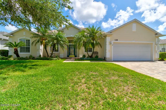 a front view of a house with a yard and palm trees