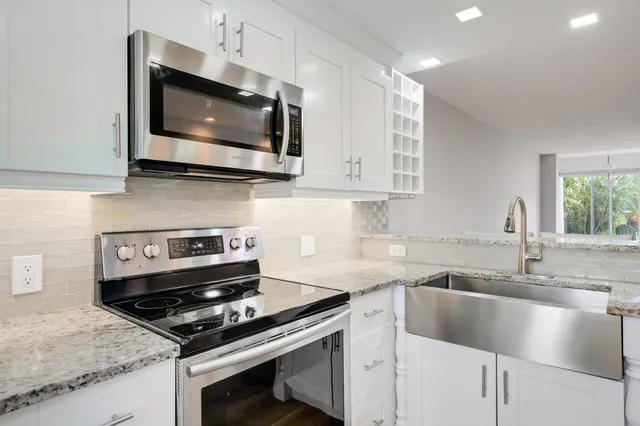 a kitchen with stainless steel appliances granite countertop a sink stove a microwave and oven