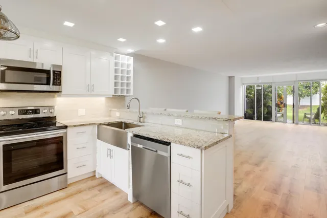 a kitchen with granite countertop stainless steel appliances a stove sink and microwave