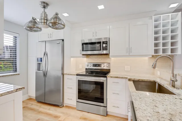 a kitchen with granite countertop a stove sink and refrigerator