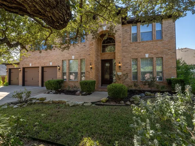a view of a brick house with a yard and large tree