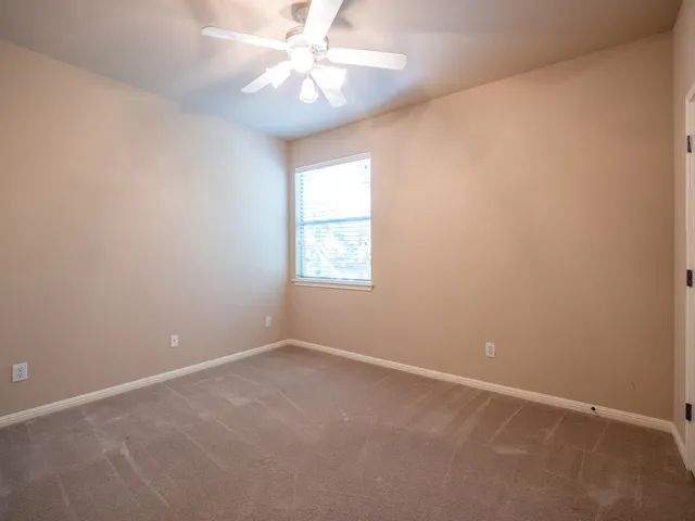 an empty room with a window and a fan