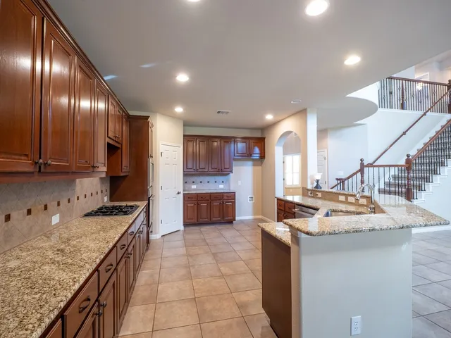 a kitchen with a stove a sink a refrigerator and chairs