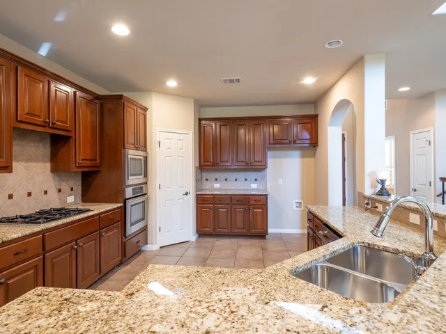 a kitchen with stainless steel appliances kitchen island granite countertop a sink stove and refrigerator
