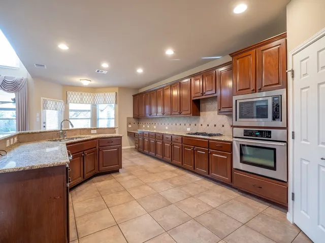 a large kitchen with stainless steel appliances granite countertop a stove sink and cabinets