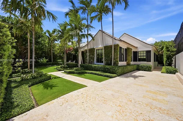 a front view of a house with a yard and potted plants