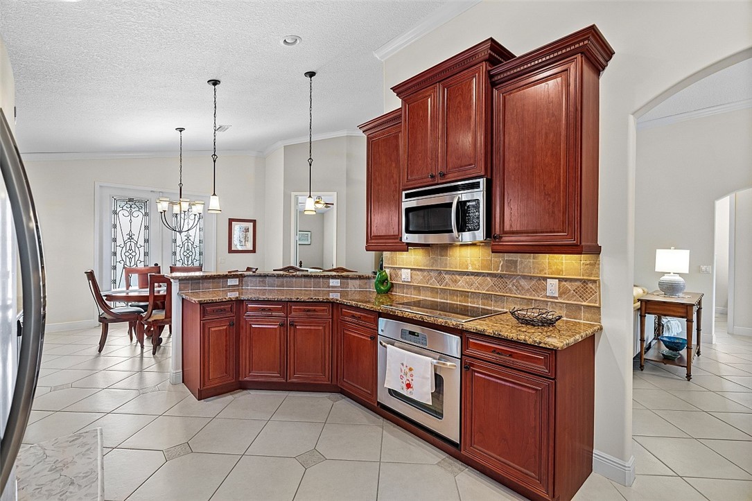 567 Gossamer Wing Way Sebastian, FL 32958 - Photo 7 of 35 a kitchen with stainless steel appliances granite countertop a stove a sink and a microwave
