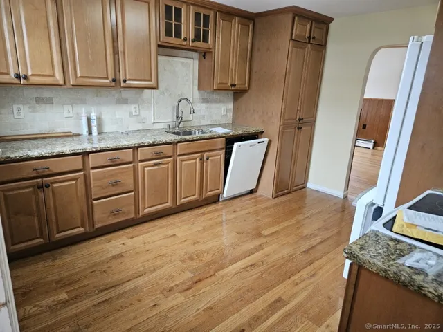 a kitchen with stainless steel appliances granite countertop a sink a refrigerator and wooden cabinets