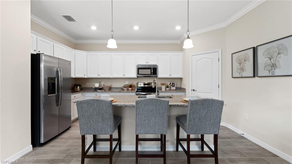 17262 Silverling Court Alva, FL 33920 - Photo 7 of 20 a kitchen with stainless steel appliances granite countertop a dining table chairs refrigerator and microwave