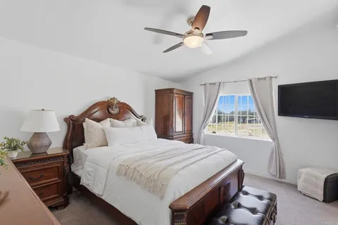 a bedroom with a bed a window and a flat screen tv