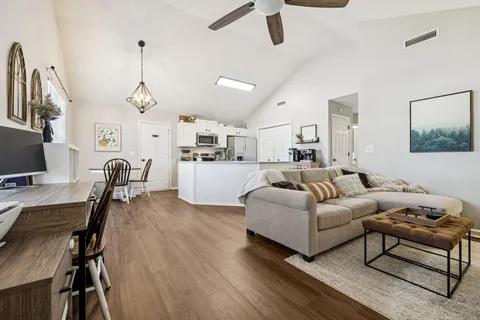 a living room with furniture kitchen view and a wooden floor