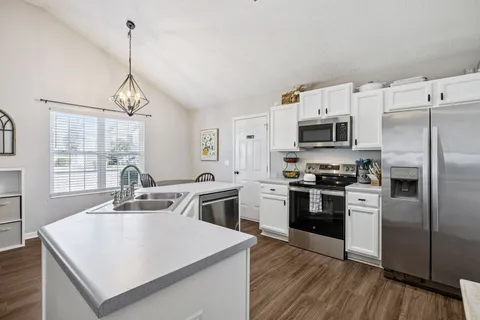 a kitchen that has stainless steel appliances a microwave a stove a sink dishwasher a refrigerator white cabinets and wooden floor