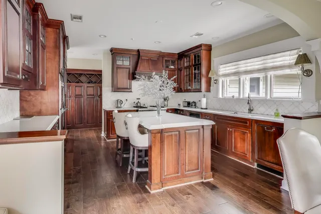 a kitchen with stainless steel appliances granite countertop a sink dishwasher a stove and a dining table with wooden floor