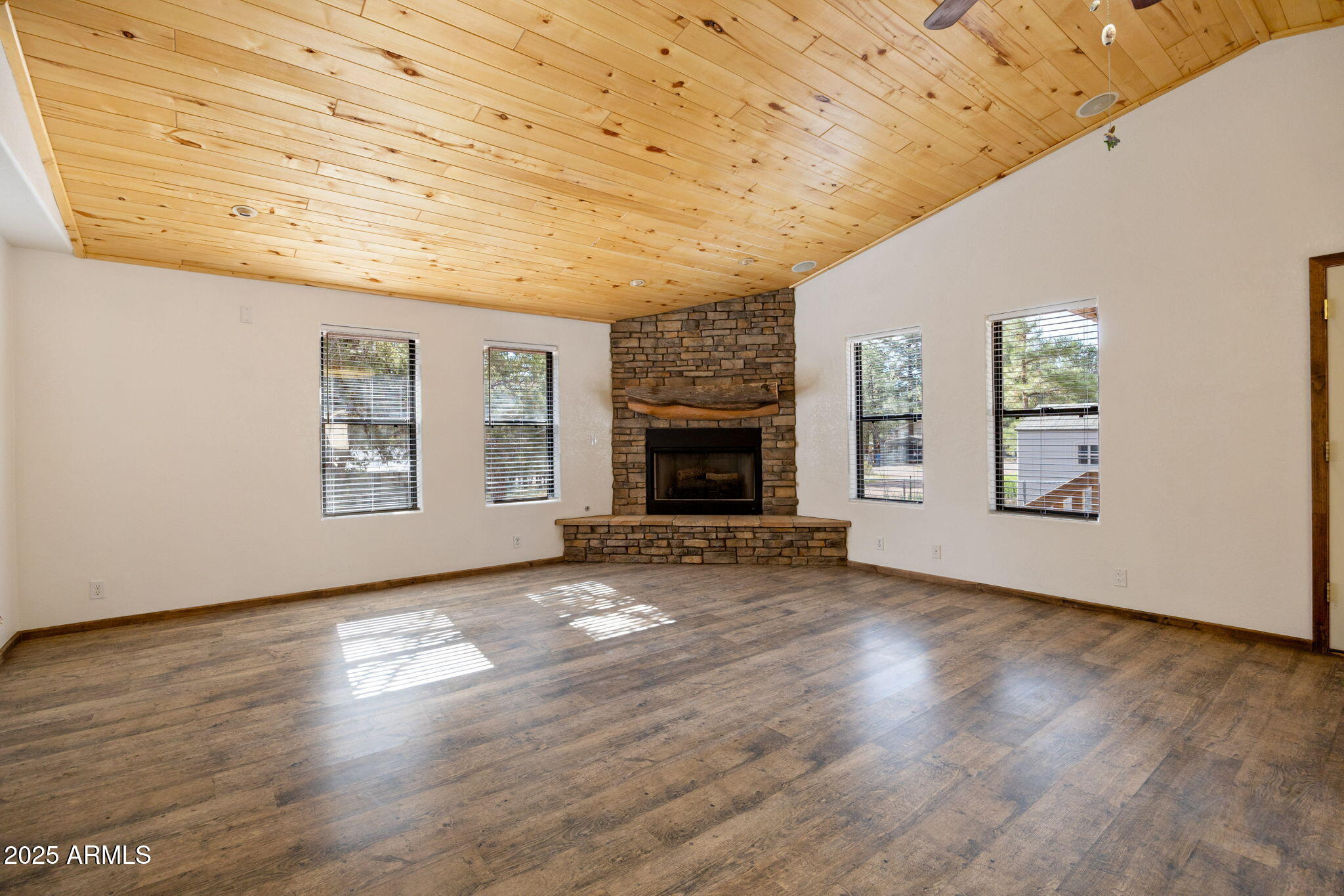 2882 Verde Road Overgaard, AZ 85933 - Photo 9 of 33 an empty room with wooden floor fireplace and windows