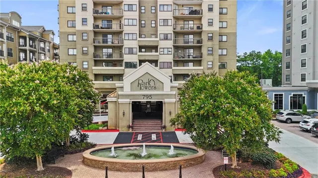 a patio with table and chairs potted plants and a building