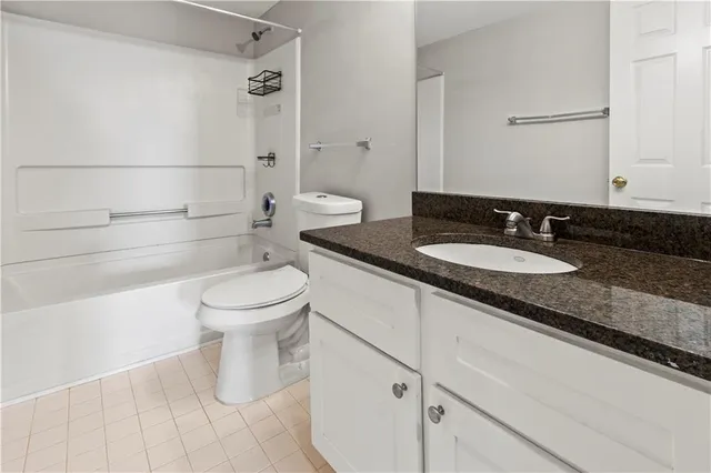 a bathroom with a granite countertop sink a toilet and a shower