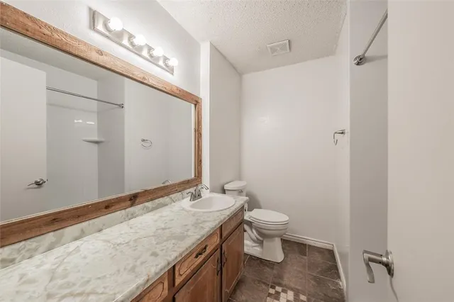 a bathroom with a granite countertop sink a toilet and a mirror