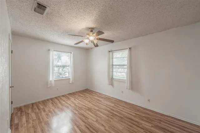 a view of an empty room with a window and a ceiling fan