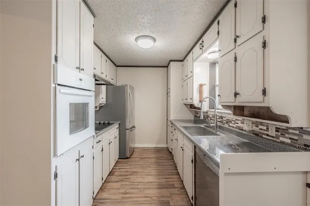 a kitchen with granite countertop a sink stove and refrigerator
