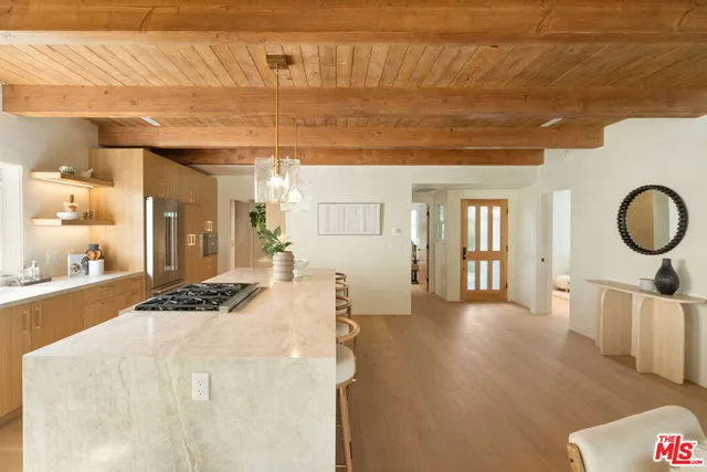 a living room with kitchen island stainless steel appliances wooden floor and living room view