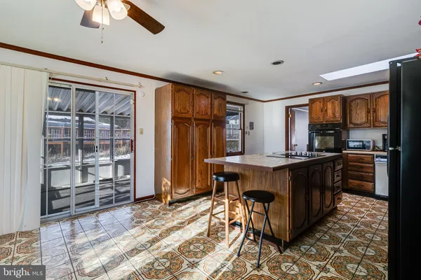 a kitchen with stainless steel appliances granite countertop a refrigerator a sink a stove a dining table and chairs with wooden floor