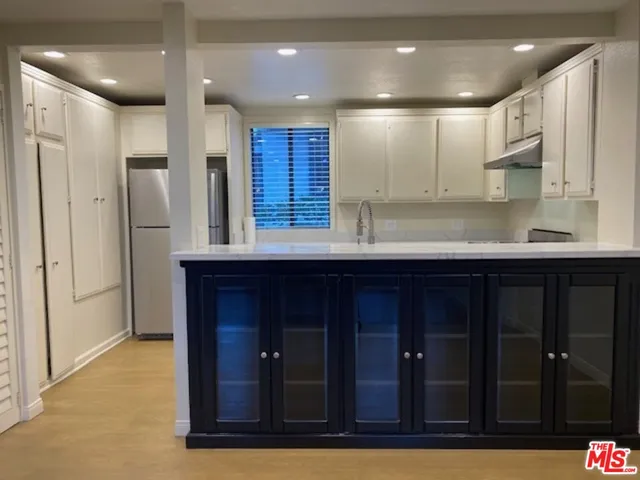 a kitchen with stainless steel appliances granite countertop wooden cabinets a refrigerator and a sink