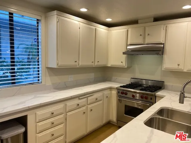 a kitchen with granite countertop a sink a stove and cabinets