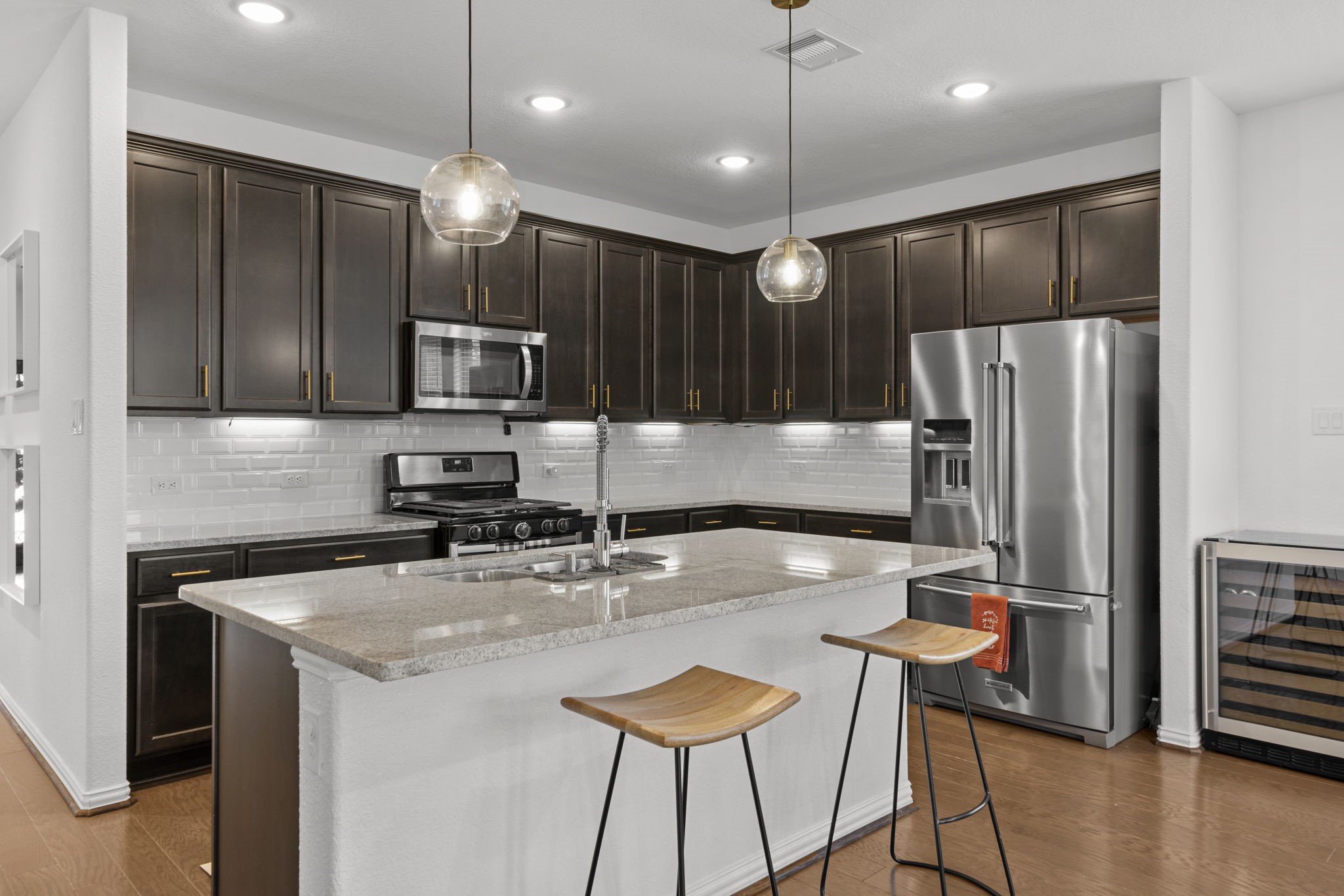 7703 Cowdray Lane Fulshear, TX 77441 - Photo 3 of 15 a kitchen with stainless steel appliances granite countertop a refrigerator a stove a sink a dining table and chairs with wooden floor