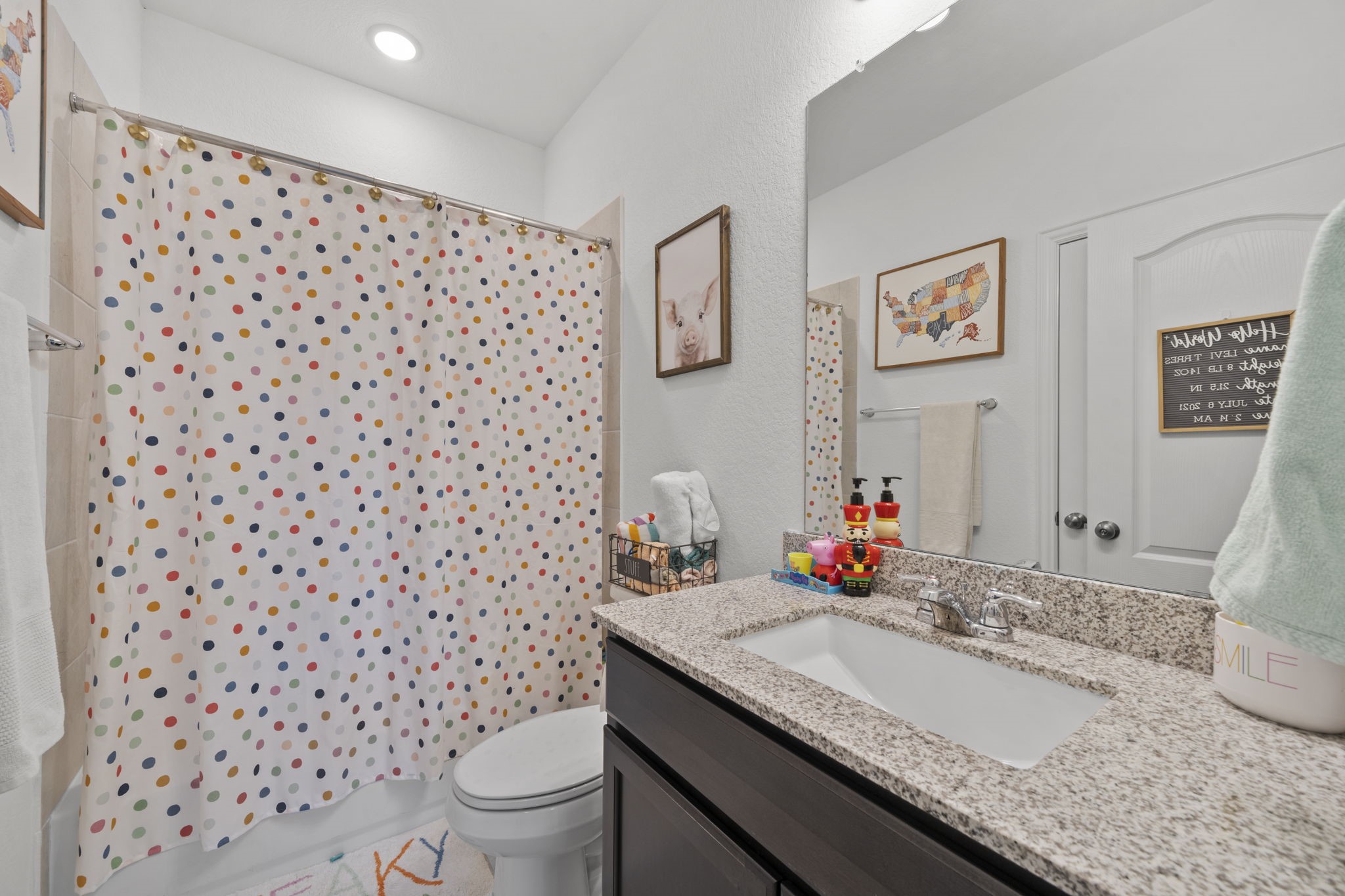 7703 Cowdray Lane Fulshear, TX 77441 - Photo 10 of 15 a bathroom with a granite countertop sink a toilet and a shower curtain