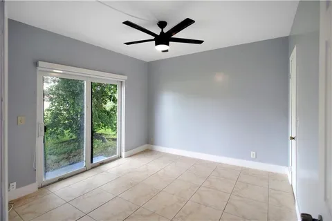 an empty room with windows and ceiling fan