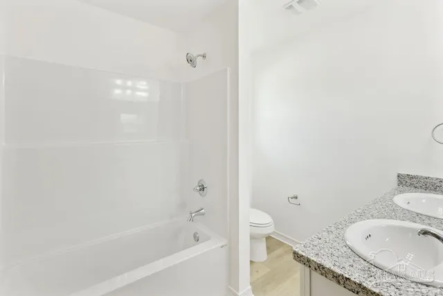 a bathroom with a granite countertop sink a toilet and bathtub