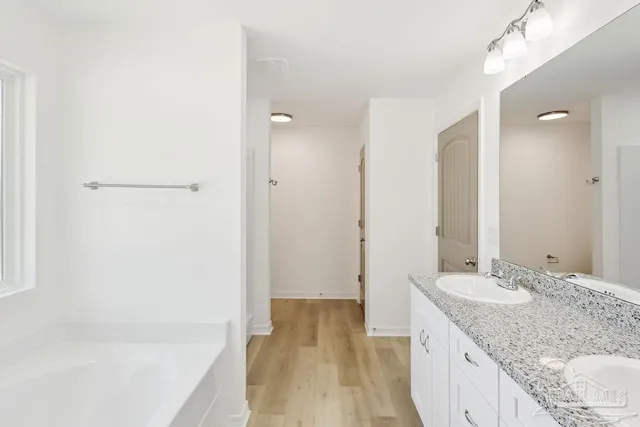 a bathroom with a granite countertop sink a mirror and a bathtub