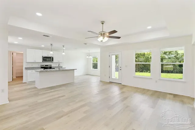 a view of an empty room with window and wooden floor