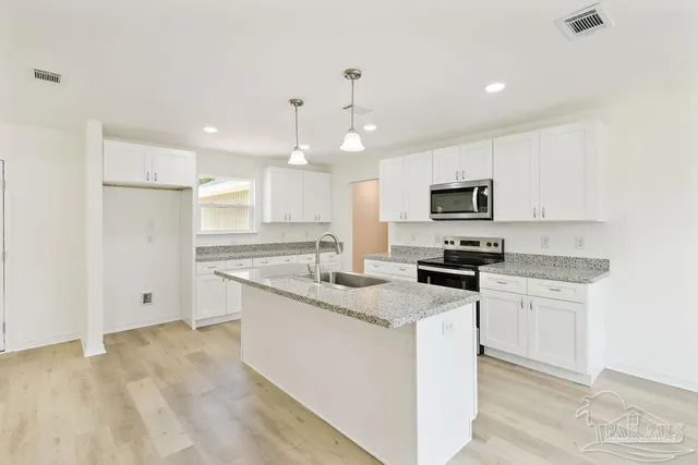 a kitchen with white cabinets appliances and sink